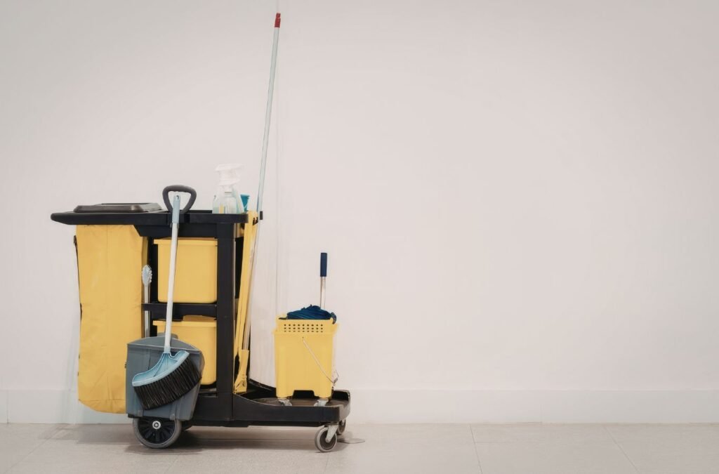 Janitorial worker inspecting high-touch surfaces with organized cleaning tools and floor equipment. Janitorial Services near me.