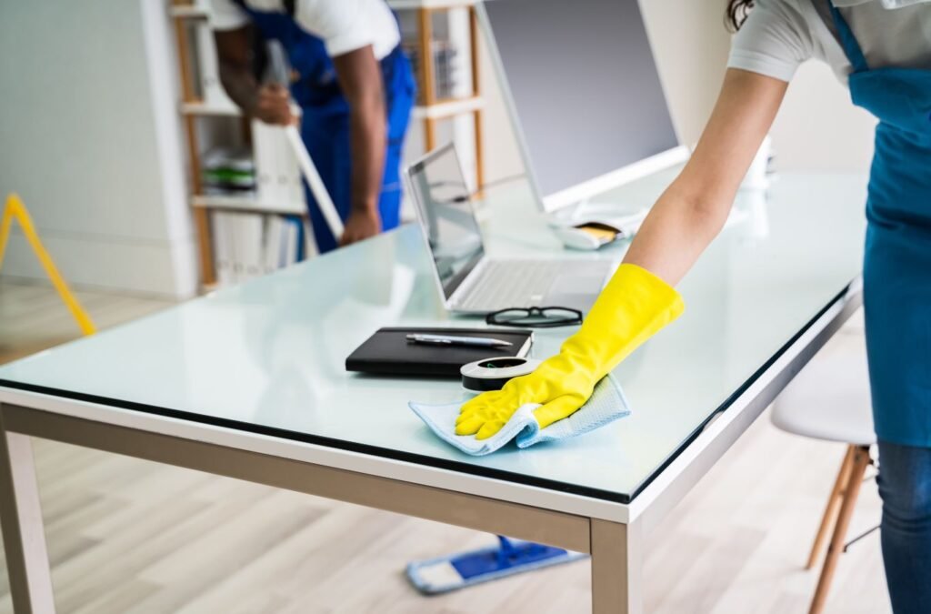 Cleaner sanitizing conference table after client meetings in busy office suite