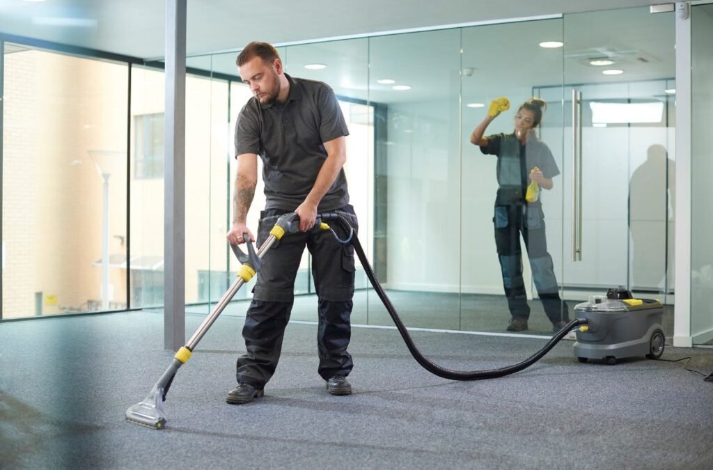 Cleaner sanitizing reception desk and glass entry before employees arrive at office